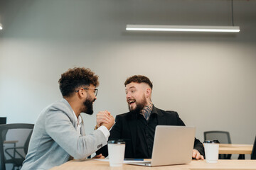Fototapeta premium Business colleagues arm wrestling in office for friendly competition