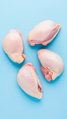 Top view of fresh raw chicken breast pieces arranged on a blue background flat lay
