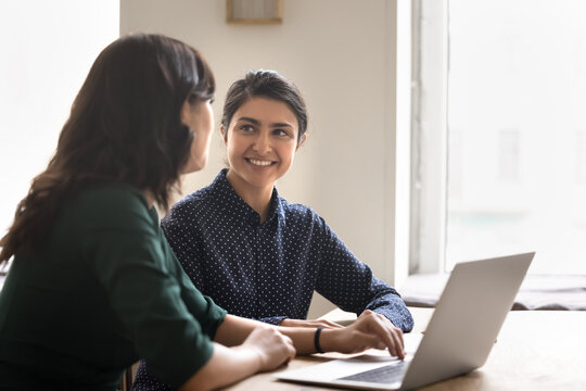 Smiling young woman intern learn from female mentor at workplace