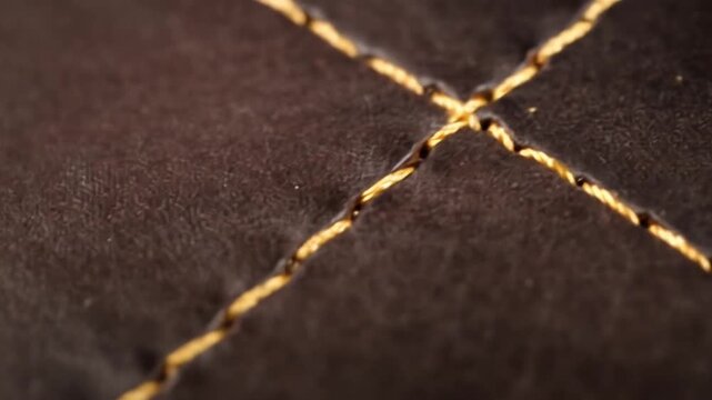 Close-up of a brown surface with a gold-colored thread stitched diagonally