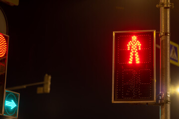 Obraz premium Red pedestrian signal at night in urban setting showing stop for walkers