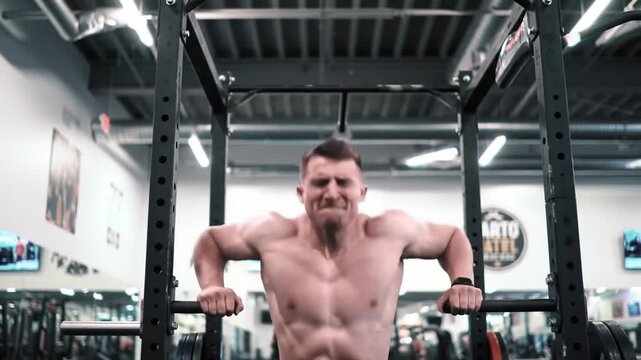 A muscular man performing dips on parallel bars in a gym, showcasing his strength and dedication to fitness.