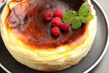 Tasty Basque cheesecake with raspberries and mint on grey table, closeup