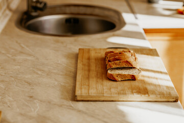 Sliced bread rests on a wooden cutting board in a cozy rustic kitchen.
