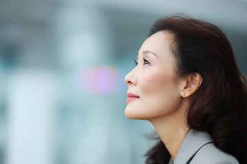 Obraz premium chinese, Side profile portrait of a business woman, 50 years old, office background with copyspace 