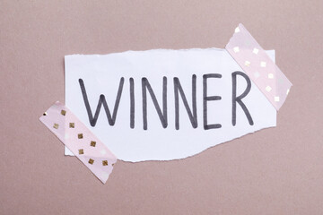 Paper note with word Winner on grey background, top view