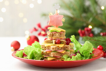 Christmas food. Fir tree made of bread, cheese, ham, lettuce and decor on white table against...