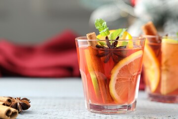 Tasty punch drink in glasses and spices on white wooden table, closeup. Space for text