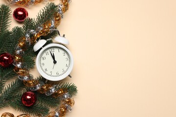 Alarm clock, fir tree branches, baubles and tinsel on beige background, flat lay with space for...