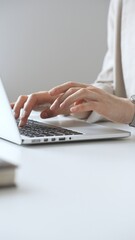 Professional businesswoman working intently on laptop, wearing tailored beige suit and silver...