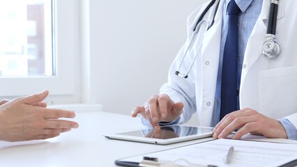 Doctor man showing information on tablet to patient woman during medical visit, explaining...