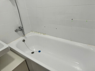 Modern white bathtub with chrome fixtures, set against tiled walls, creating a clean and bright bathroom atmosphere, ideal for relaxation and comfort