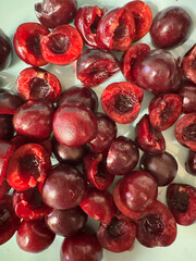 Vibrant red cherry halves are artistically arranged on a light surface, showcasing their juicy texture and natural sweetness, perfect for culinary inspiration