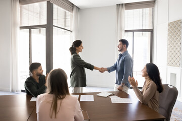 Company boss greeting new employee during group meeting