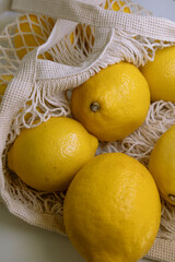 Fresh Yellow Lemons in Trendy Mesh Bag – Flat Lay on White Background with Copy Space