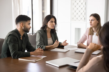 Business team listening colleague at conference desk in modern office