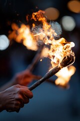 Hands holding flaming torches during a fire juggling performance, blurred flames and dark background, concept of danger, skill and entertainment