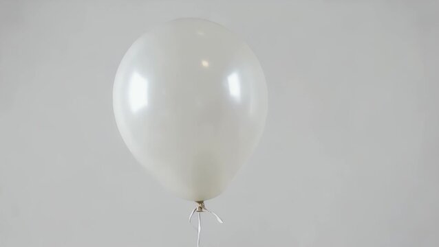 solitary white gas-filled balloon tethered by a string  isolated on a plain white