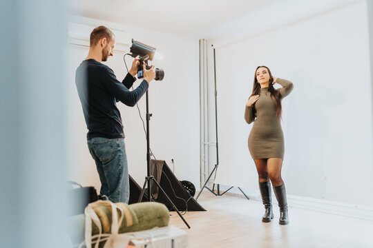 Photographer capturing a model posing in a well equipped studio setting with lighting equipment. The model displays confidence, showcasing a perfect collaboration for fashion, portrait or commercials.