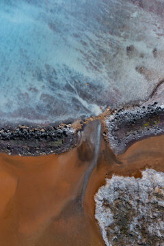 Aerial view of otherworldly landscapes where turquoise waters meet rust-colored earth in a striking, textural contrast, Geothermal Areas, Iceland.