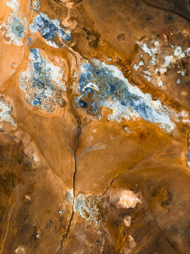 Aerial view of a tapestry of earthy browns and vibrant blues mingle in a geothermal landscape, creating an otherworldly spectacle, Geothermal Areas, Iceland.