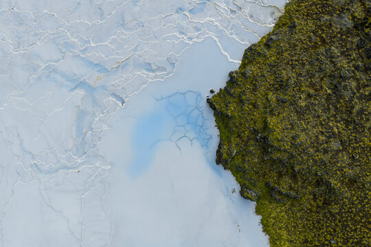 Aerial view of the contrasting textures of moss-covered rocks against the milky blue waters, creating a stunning visual dichotomy, Geothermal Areas, Iceland.