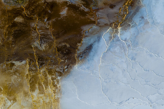 Aerial view of earth's canvas painted with strokes of rust and gold, where geothermal veins pulse beneath a pale sky, Geothermal Areas, Iceland.