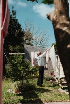 Um homem pendurando roupas em um varal no quintal de sua casa.