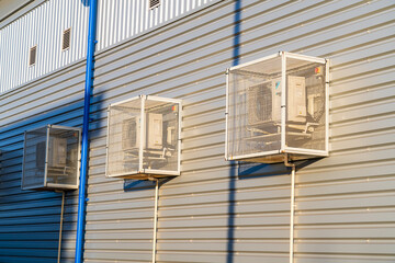 Air conditioning units on the side of a building with steel mesh cages to protect from vandalism