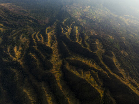 Aerial view of a rugged landscape with deep shadows and golden highlights creating a dramatic contrast, Mount Ijen, East Java, Indonesia.