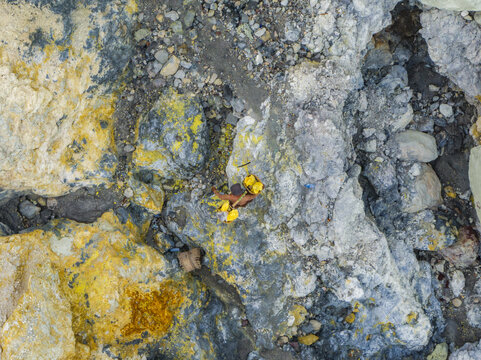 Aerial view of the terrain's stark contrast between the bright yellow sulphur deposits and the cool grey rocks, Mount Ijen, East Java, Indonesia.