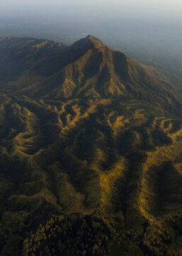 Aerial view of the majestic Mount Ijen, where rugged peaks rise amidst verdant slopes, contrasting shadows and sunlight dance across the landscape, Mount Ijen, East Java, Indonesia.