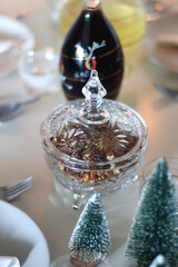 Table set for Christmas meal, with plates, wine, decorations and lit candles. Selective focus.