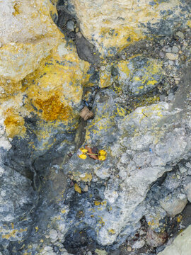 Aerial view of mineral deposits painted with vibrant yellow and grey, creating a harsh yet beautiful landscape, Mount Ijen, East Java, Indonesia.