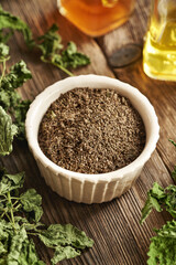 Stinging nettle seeds in a bowl with dried leaves on a table