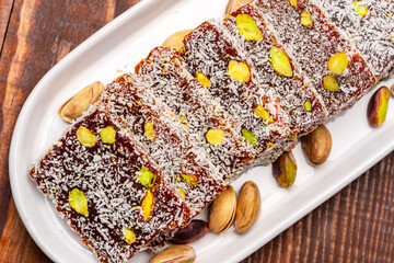 Turkish delight cezerye with pistachio or hazelnut on wooden background. Cezerye, a traditional dessert from the Mersin region
