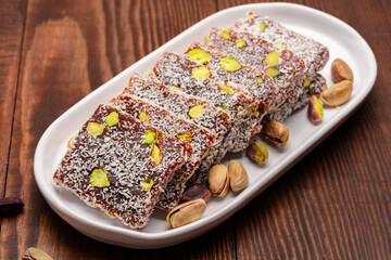 Turkish delight cezerye with pistachio or hazelnut on wooden background. Cezerye, a traditional dessert from the Mersin region