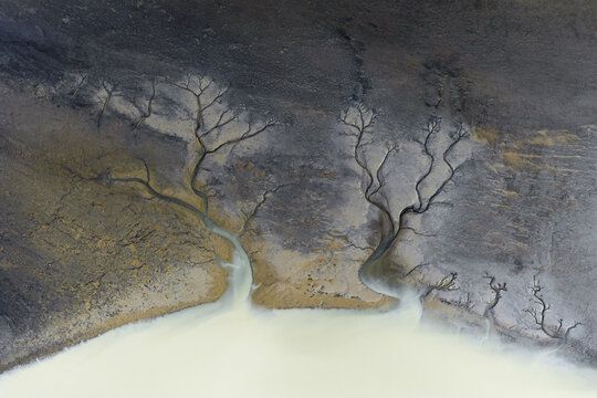 Aerial view of glacial rivers carving intricate patterns into the volcanic landscape, like veins on the earth's surface, South Coast, Iceland.