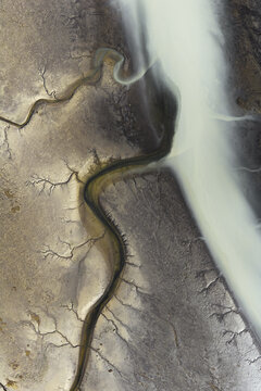 Aerial view of glacial river carving intricate paths through the stark, contrasting landscape of the South Coast, Iceland, South Coast, Iceland.