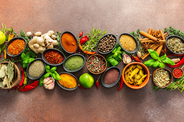 A stunning spread of fresh spices and herbs, meticulously arranged on a deep brown backdrop, capturing their vibrant colors and tantalizing aromas