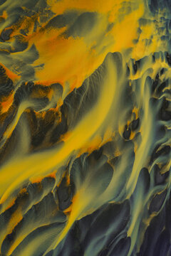 Aerial view of vibrant, contrasting hues of yellow and grey interweave across the braided river system, creating a mesmerizing tapestry of nature's artistry, South Coast, Iceland.