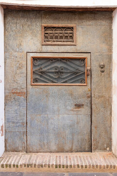 antigua puerta con plancha de metal, ventanuco en su parte superior