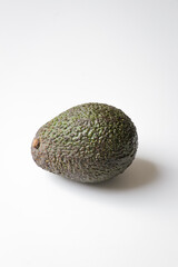 Avocado with skin on white background. Vegetarian, vegan diet ingredient, healthy food, breakfast brunch lunch recipe with organic superfood green vegetables. Vertical portrait photo.