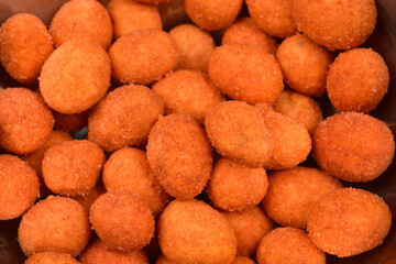 An extreme close-up, full frame shot of numerous orange, coated peanuts, showcasing their crunchy, textured surface
