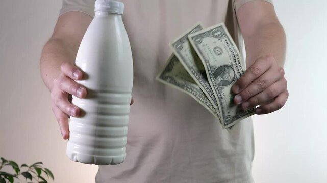 Dynamic slow motion video of a mans hands presenting two elements of value: a pristine white dairy bottle and paper currency. This conceptual shot symbolizes tangible returns, product quality, and