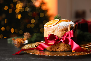 Christmas food. Delicious Panettone cake, ingredients and festive decor on black table against...