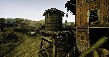 Wooden buildings and a grain silo characterize this old western town. A dirt path leads through the settlement, surrounded by rugged hills under a clear sky. © icetray