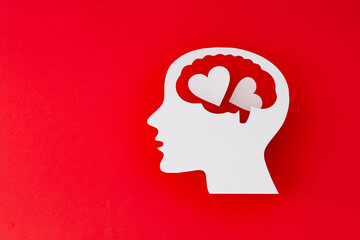 Profile of paper human head with hearts on red background. Love in the mind concept. Symbolic representation of romantic feelings, emotional intelligence and psychological health.
