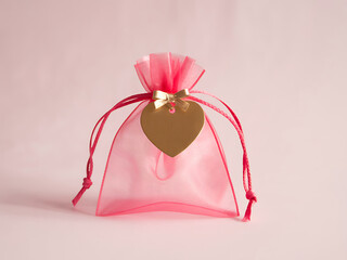 Small pink organza gift bag with a golden heart charm and red drawstring