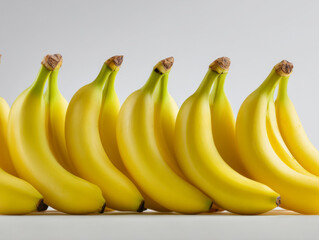 Fresh ripe yellow bananas neatly arranged in a row against a plain white background showcasing their smooth vibrant peels and natural curved shapes